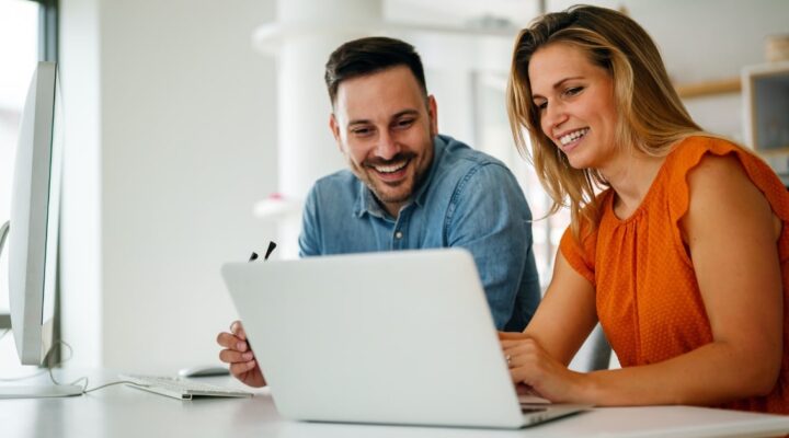 two coworkers using a tool for better document management in the office using a laptop