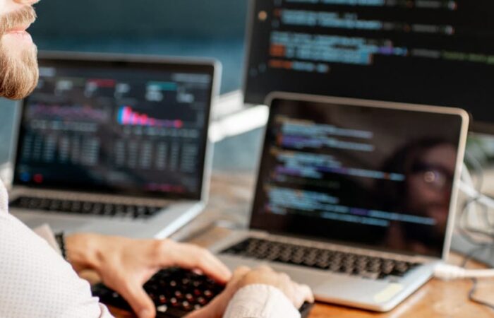 handsome man putting code into multiple devices