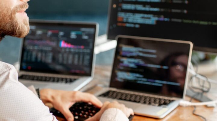 handsome man putting code into multiple devices