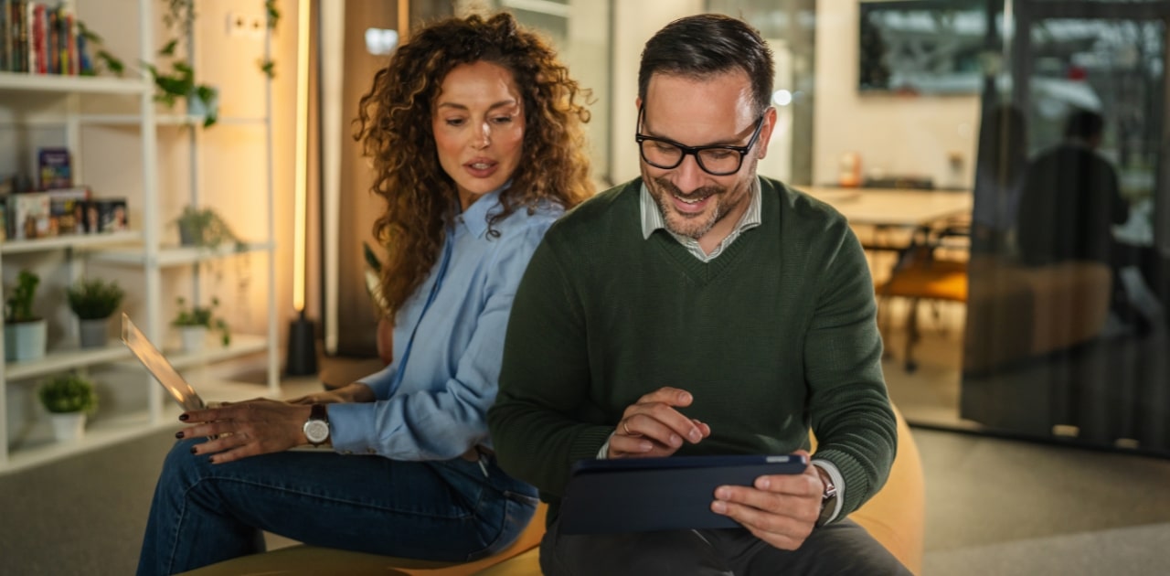 businessman and businesswoman discussing next business meeting on a laptop and tablet sitting in a cozy office